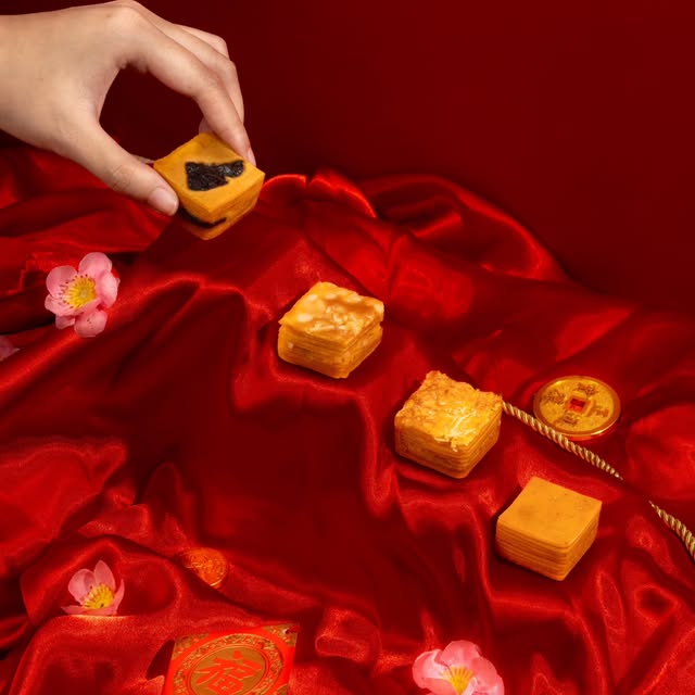 Lapis legit potong di atas kain satin merah dengan bunga sakura